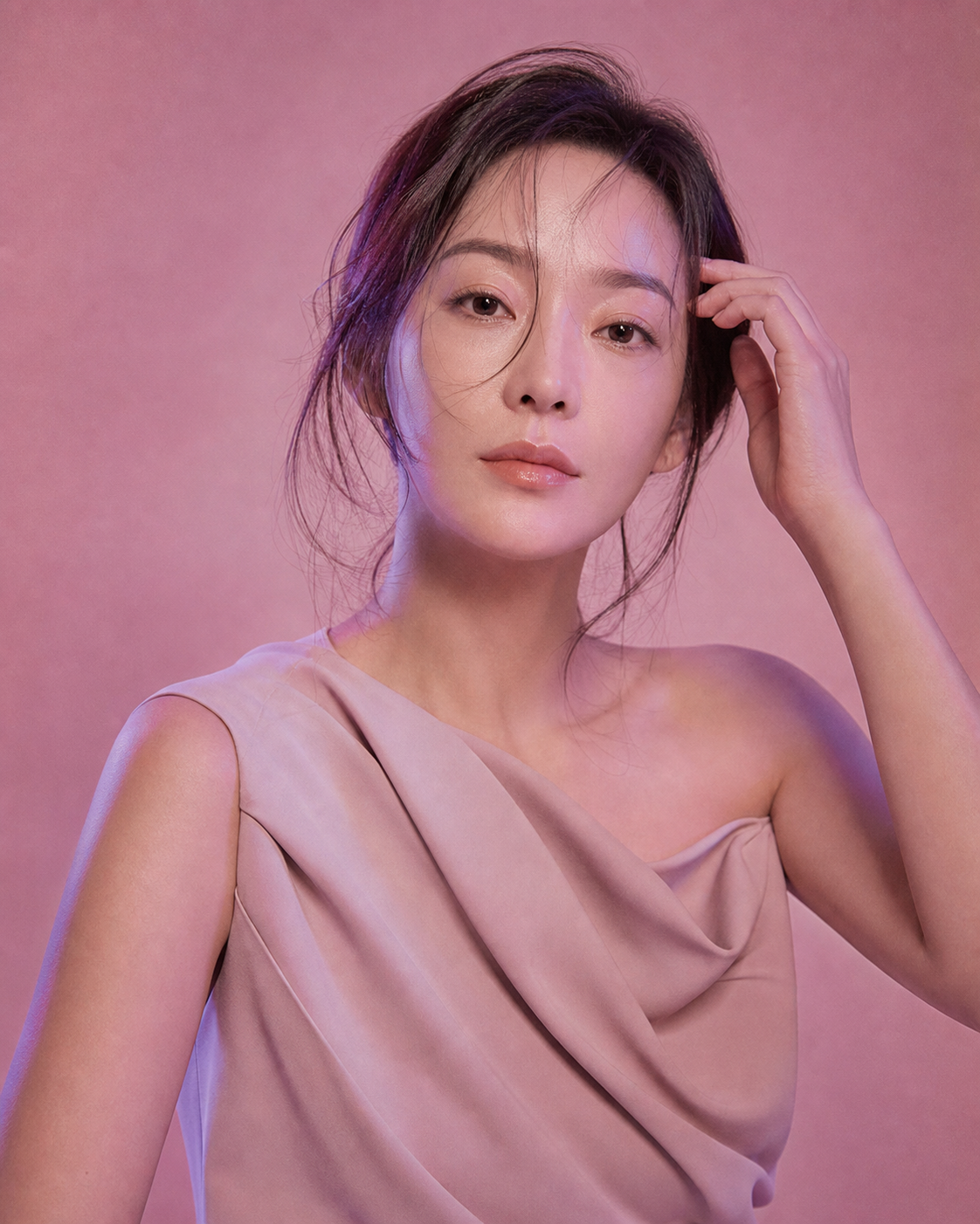 분홍빛과 보랏빛 조명 아래 머리카락을 정리하며 정면을 바라보는 성인 여성의 에디토리얼 인물 화보